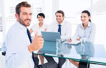 Group in a meeting room, person giving thumbs up