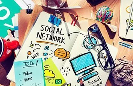 Desk with notebook titled 'Social Network' surrounded by notes and office supplies.