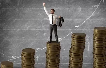 Person standing on stacks of coins with an upward graph in the background.