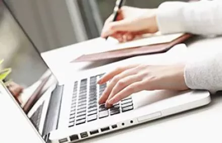 Personne tapant sur un ordinateur portable sur un bureau.
