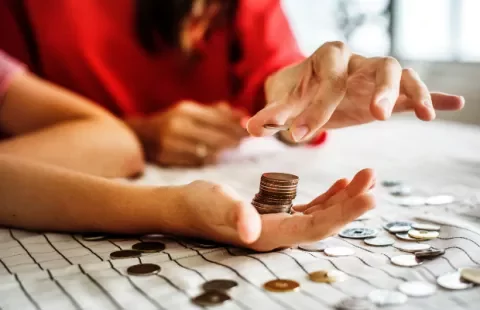 Hands counting coins on a table.