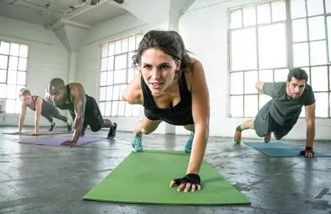 Groupe faisant de l'exercice à l'intérieur, en position de planche sur des tapis de yoga.