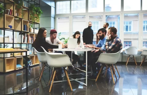 Groupe de collègues collaborant autour d'une table dans un bureau moderne.